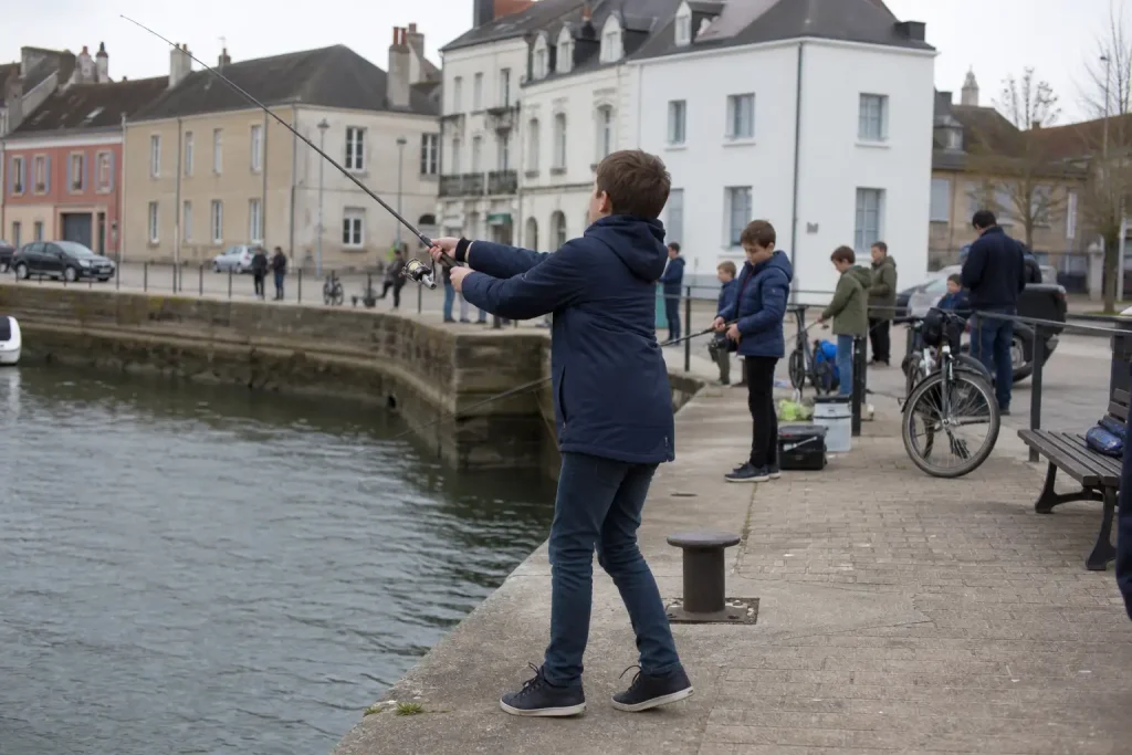 Barn kastar med spinnspö vid kajen under streetfisketävling Smålandsborren en solig eftermiddag.