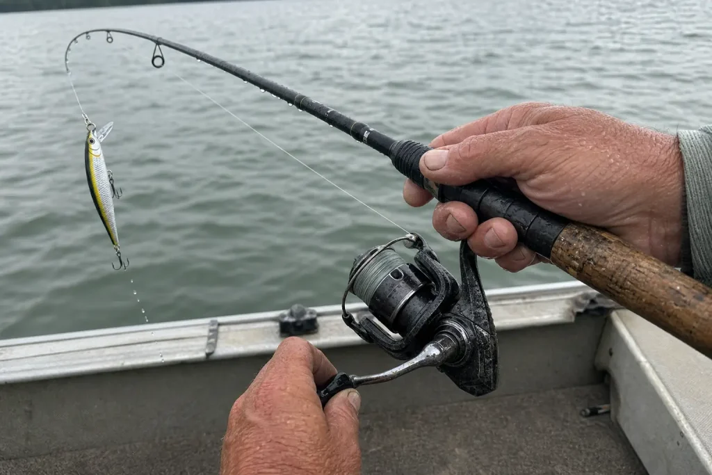 Blöta händer håller ett spinnfiskespö med jerkbait mitt i drag, ett exempel från Vilka köder vi använder i september 2026